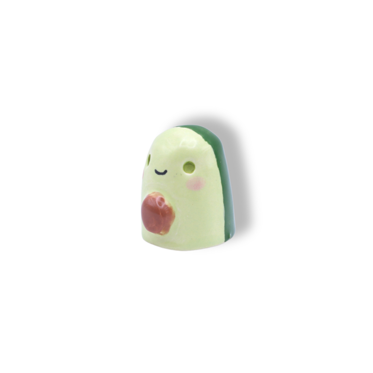 A small ceramic figurine of an avocado with a smiling face and a heart detail on its side.