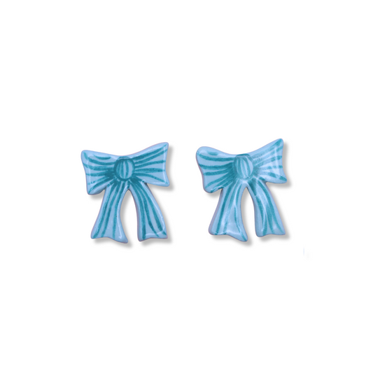 A pair of blue ceramic bow-shaped stud earrings on a white background.