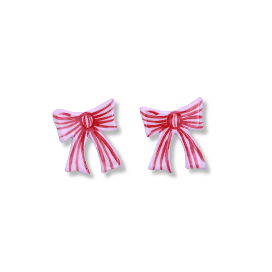 A pair of pink ceramic bow-shaped stud earrings on a white background.